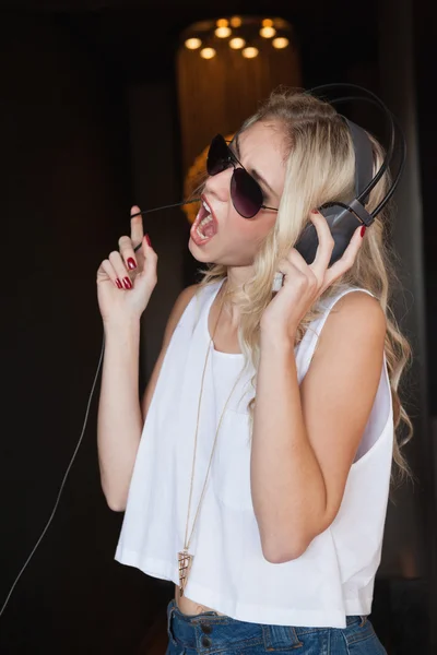 Ładna blondynka w okulary, słuchanie muzyki i śpiewu — Zdjęcie stockowe