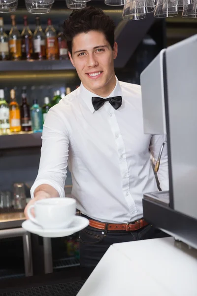 Joven barista ofreciendo taza de café sonriendo a la cámara — Foto de Stock