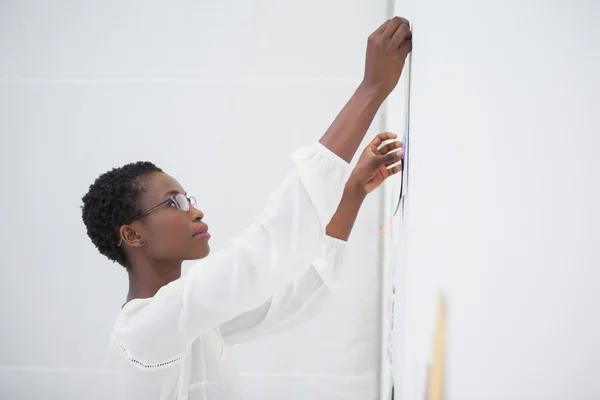 Businesswoman with glasses pinning paper up — Stock Photo, Image