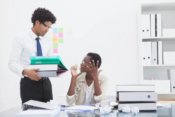 Mann gibt seinem genervten Kollegen Aktenstapel — Stockfoto