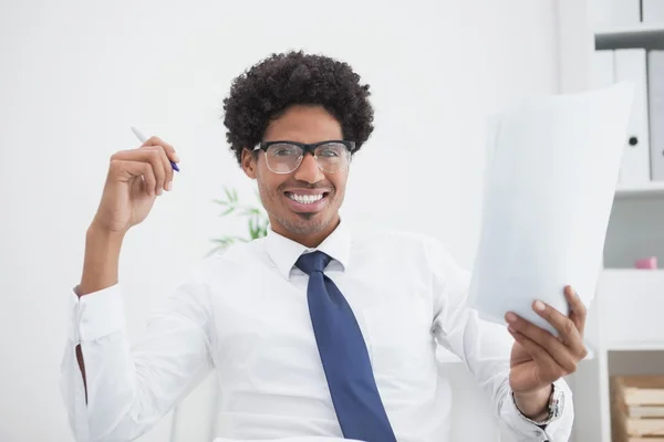 Hombre de negocios sonriente sosteniendo papel y pluma — Foto de Stock