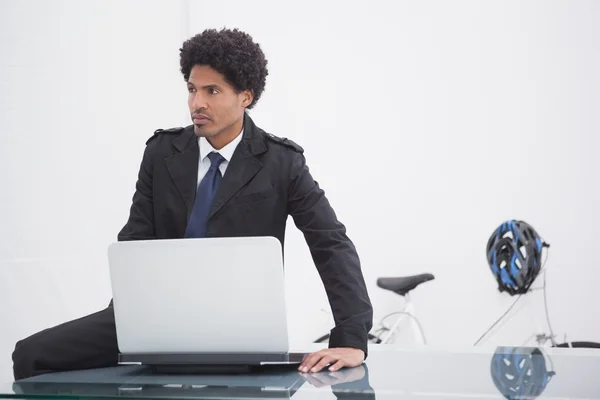 Myślący biznesmen w płaszczu przy użyciu laptopa — Zdjęcie stockowe