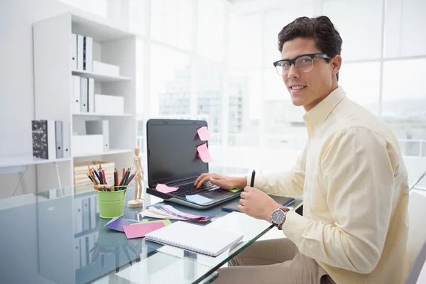 Designer utilizzando il computer portatile e sorridendo alla fotocamera — Foto Stock