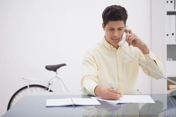 Empresário alegre ao telefone tomando nota — Fotografia de Stock