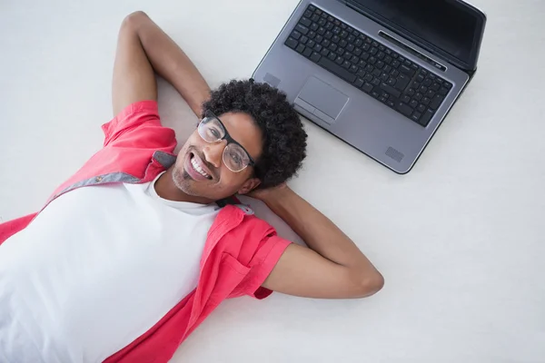 Glücklicher Geschäftsmann, der neben seinem Laptop liegt — Stockfoto