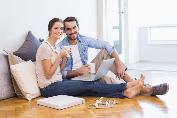 Bonito casal sentado no chão usando laptop — Fotografia de Stock