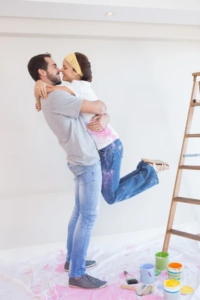 Bonito casal abraçando enquanto redecorando — Fotografia de Stock
