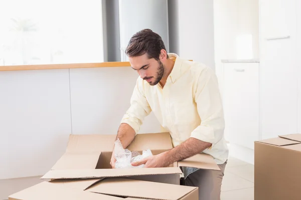 Молодий чоловік розпаковує коробки на кухні — стокове фото