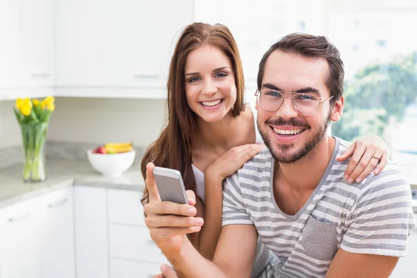 Giovane coppia sorridente alla fotocamera uomo in possesso di smartphone — Foto Stock