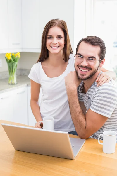 Pareja joven sonriendo a la cámara usando el portátil —  Fotos de Stock