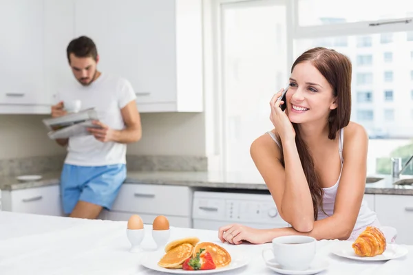 Young woman talking on phone at breakfast — Stock Photo, Image