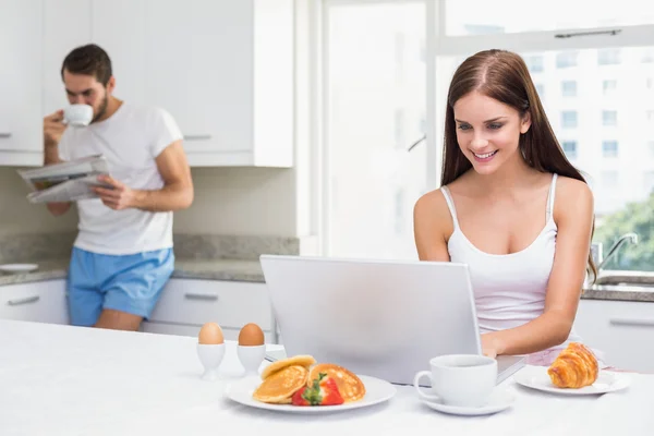 Jovem mulher usando laptop no café da manhã — Fotografia de Stock