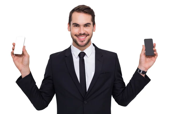 Empresário sorridente segurando móvel em cada mão — Fotografia de Stock