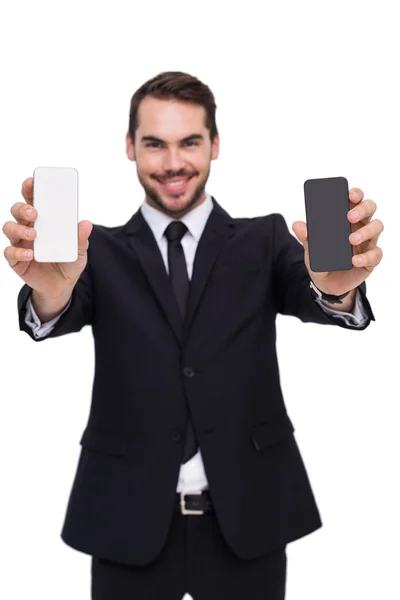 Smiling businessman showing mobile in each hand — Stock Photo, Image