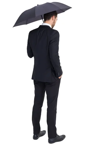 Задумчивый бизнесмен под зонтиком с рукой в кармане — стоковое фото