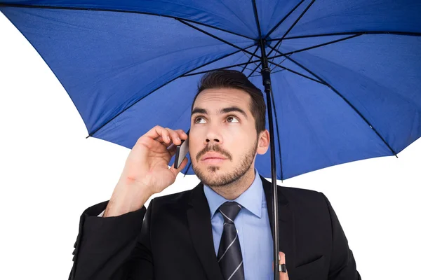 Homme d'affaires sérieux sous parapluie téléphone — Photo