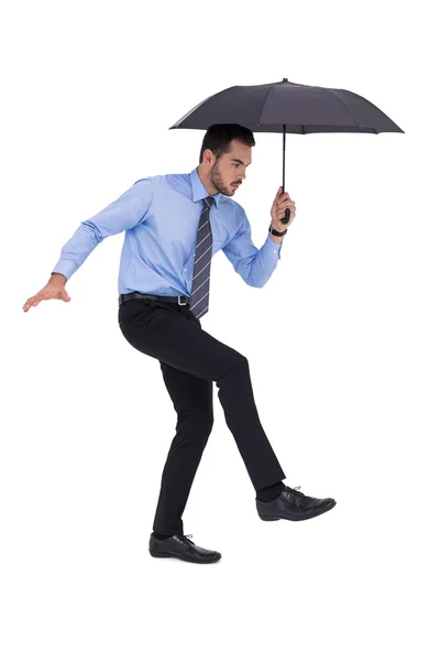 Focused businessman holding umbrella and balancing — Stock Photo, Image