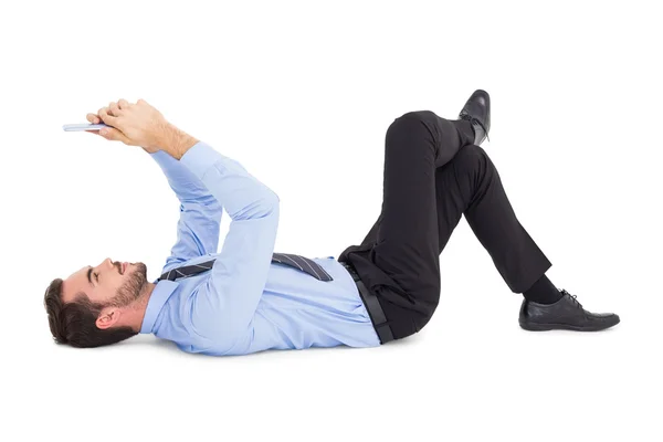 Веселый бизнесмен лежит на полу с помощью планшета — стоковое фото
