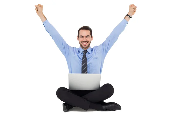 Smiling businessman sitting on the floor cheering — Stock Photo, Image