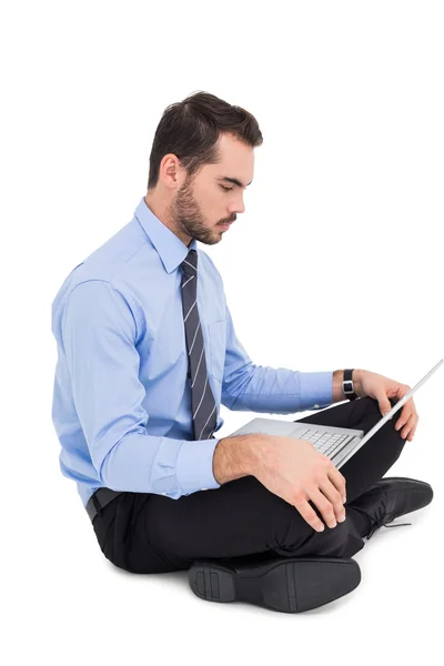 Hombre de negocios alegre sentado en el suelo usando el ordenador portátil — Foto de Stock