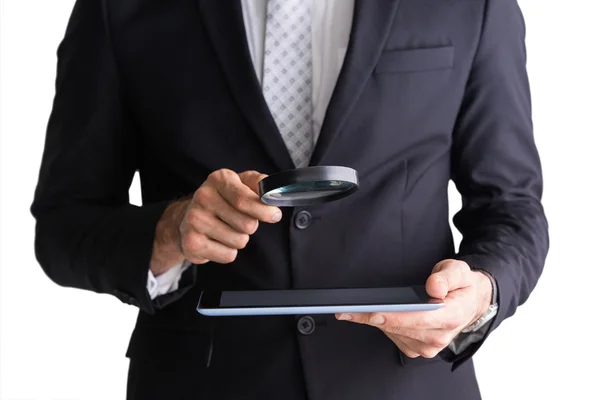 Businessman using magnifying glass and tablet — Stock Photo, Image