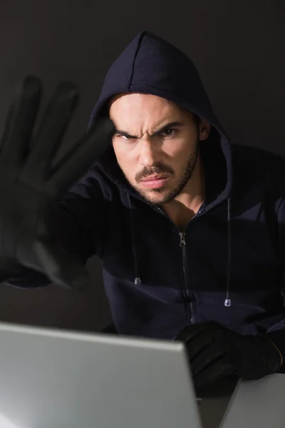 Hacker zit aan Bureau hacken een laptop — Stockfoto