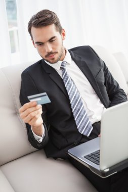Businessman shopping online on his couch clipart