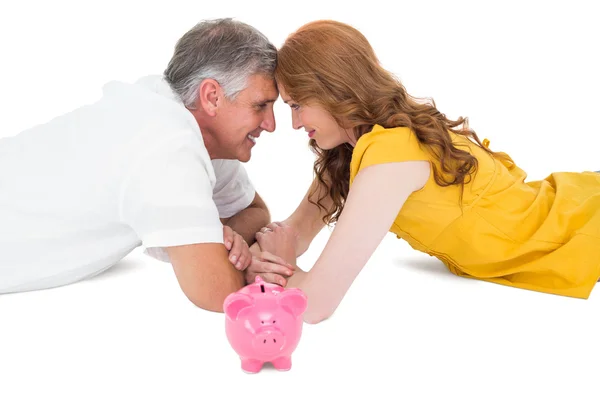 Casual couple lying on floor with piggy bank — Stock Photo, Image