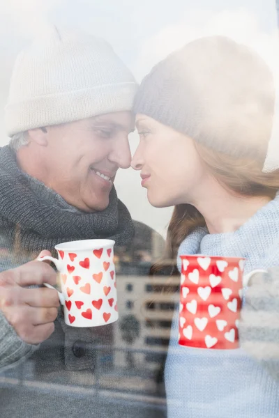 Happy couple in warm clothing holding mugs — Stock Photo, Image