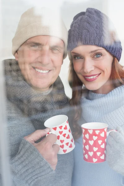 幸福的夫妇在暖和的衣服，拿着杯子 — 图库照片