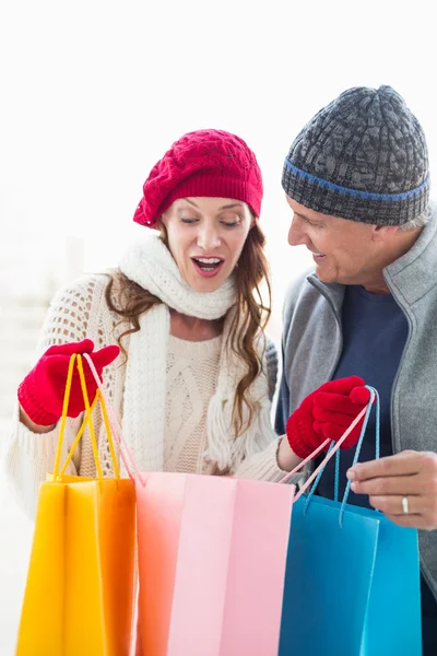 Gelukkige paar in warme kleding opening shopping tassen — Stockfoto