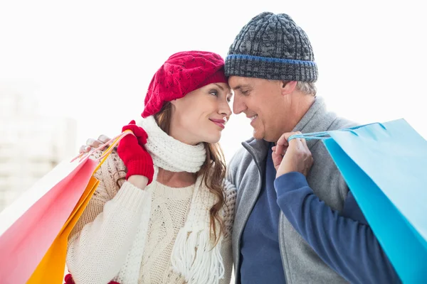 Happy couple in warm clothing with shopping bags — Stock Photo, Image