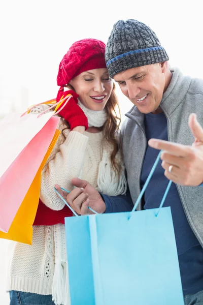 Gelukkige paar in warme kleding met shopping tassen — Stockfoto