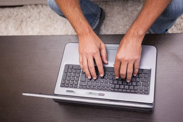 Man using his laptop on coffee table — Stock Photo, Image