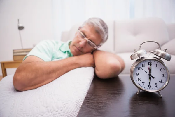 Homem dormindo no sofá ao lado do despertador — Fotografia de Stock