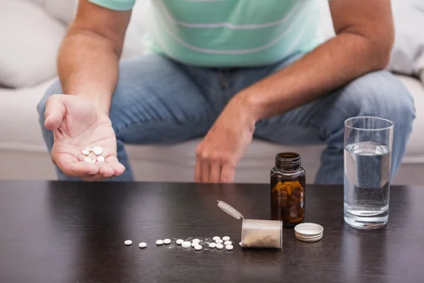 Hombre con su medicina puesta en la mesa de café — Foto de Stock