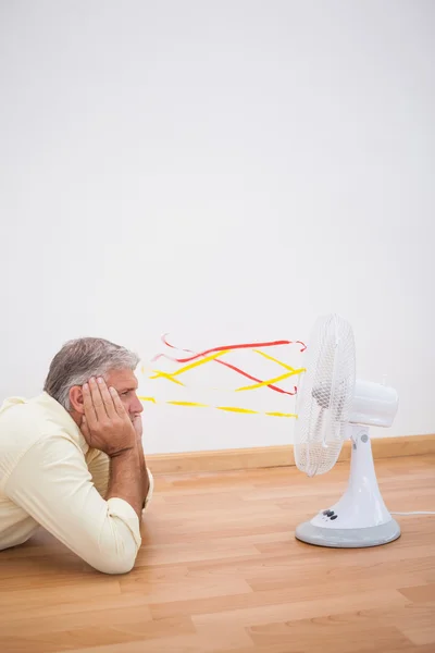 Uomo sdraiato sul pavimento a guardare ventilatore — Foto Stock