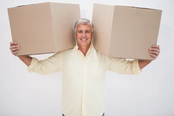 Усміхнений чоловік балансує важкі картонні коробки — стокове фото