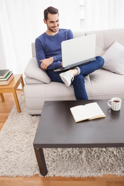 Усміхнений молодий чоловік використовує свій ноутбук — стокове фото