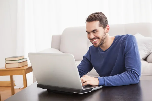 Leende ung man använder sin laptop — Stockfoto