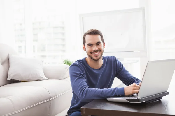 Lächelnder junger Mann mit seinem Laptop — Stockfoto