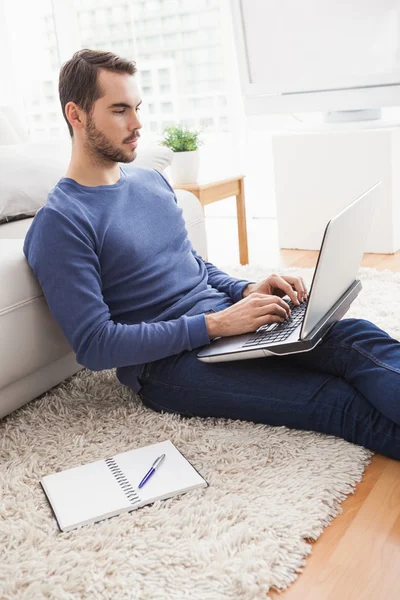 Ung man sitter på golvet med laptop — Stockfoto