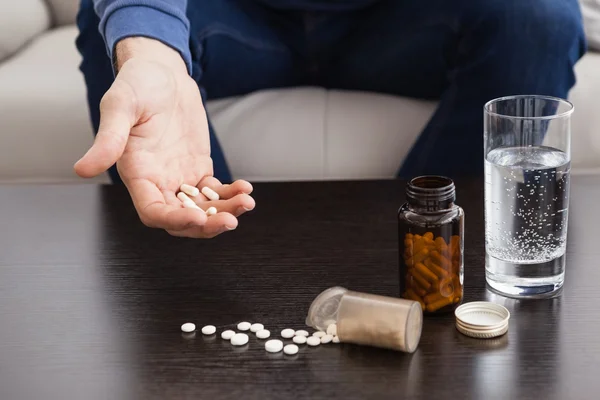 Homme avec son médicament posé sur la table basse — Photo