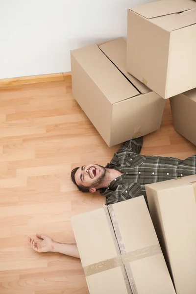 Homme couché sous des boîtes tombées — Photo