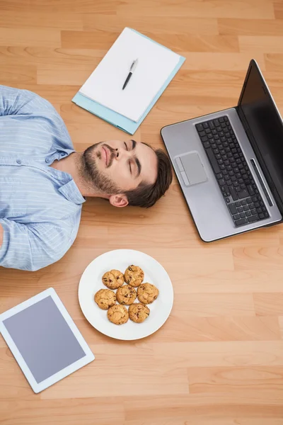 Casual man lying on floor surrounded by his possesions — Stock Photo, Image
