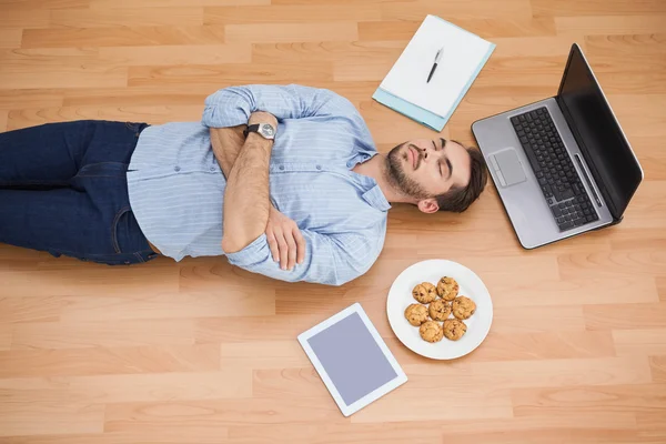 Casual man liggande på golvet omgiven av hans ägodelar — Stockfoto