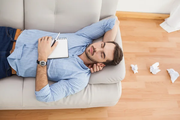 Casual man som ligger på soffan med skrynkligt papper — Stockfoto