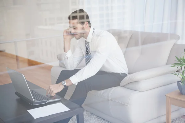 Empresário trabalhando em seu sofá visto através de vidro — Fotografia de Stock