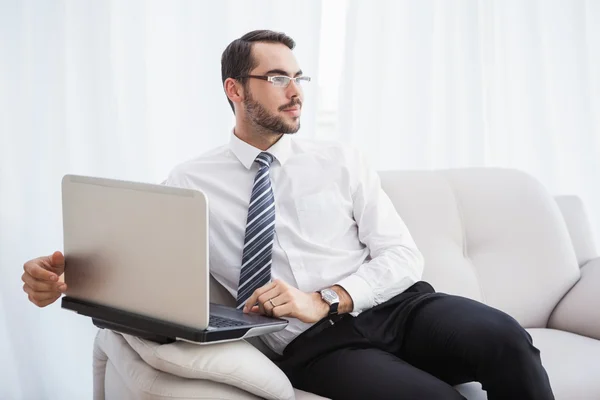 Businessman using laptop on his couch — Stock Photo, Image