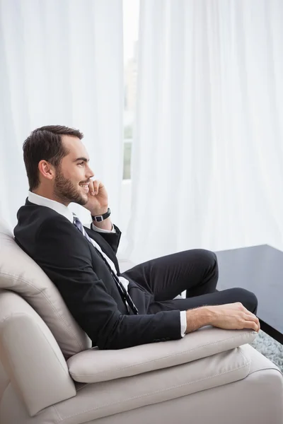 Χαμογελώντας επιχειρηματίας που πραγματοποιείτε μια κλήση στον καναπέ του — Φωτογραφία Αρχείου